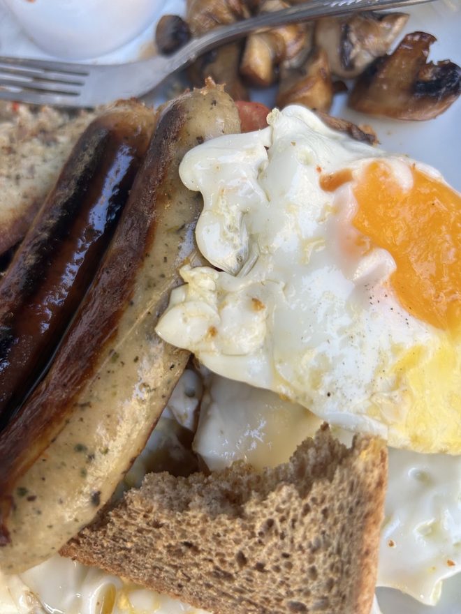 Close crop of sausages, a fried egg and mushrooms on brown toast