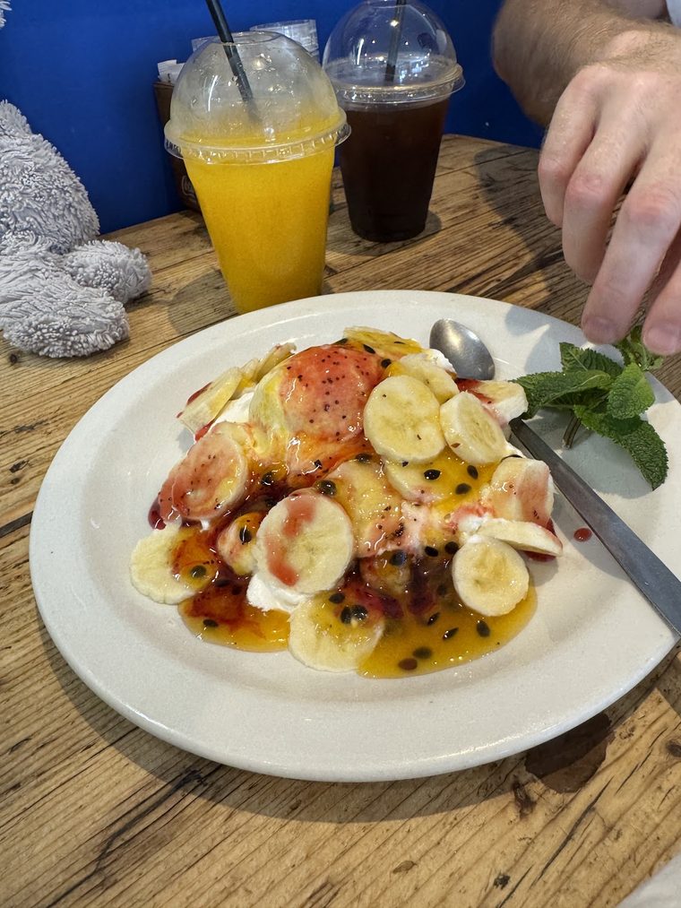 A fresh fruit and banana plate served with orange juice and an iced coffee