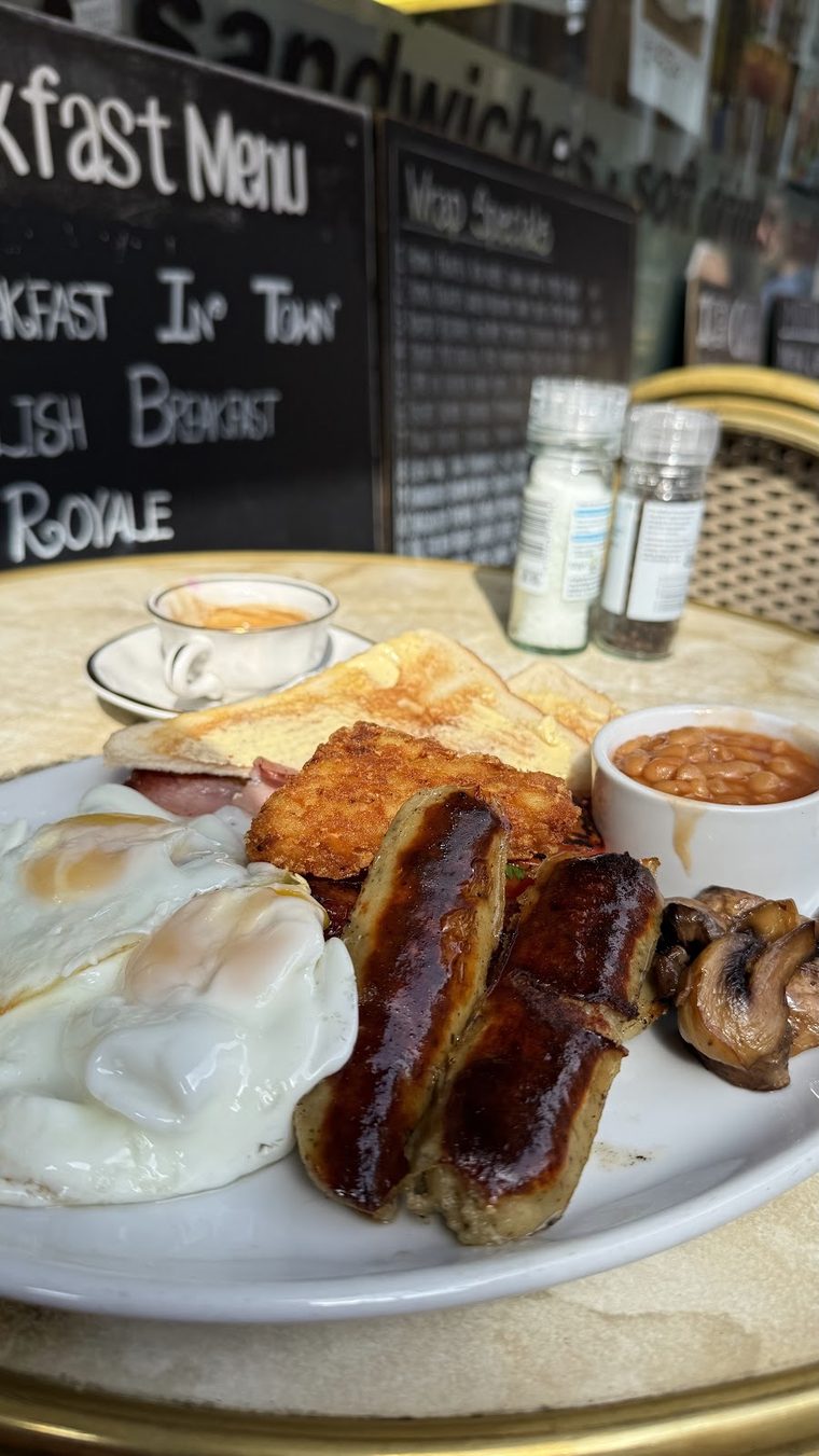 A breakfast plate with sausages, poached eggs, mushrooms and beans
